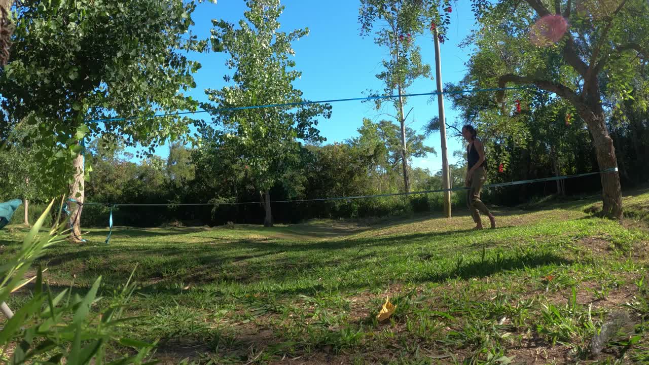 tiro de lapso de tiempo de mujer joven aprendiendo slackline en parque natural durante el hermoso día soleado