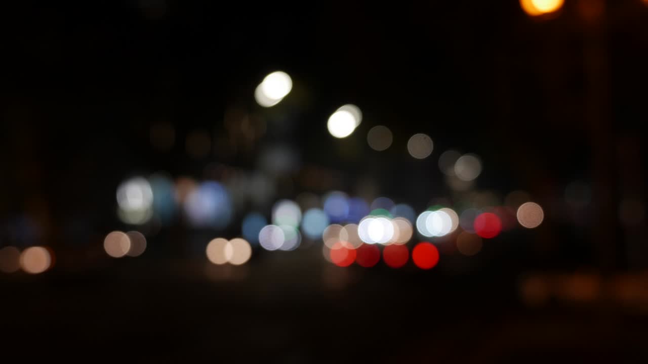 hermoso bokeh brillante en el fondo oscuro borroso por la noche. el redondo bokeh colorido brilla de las luces de los coches en la calle de la ciudad. fuera de foco con borroso. luces de la ciudad sin enfoque. bokeh de tráfico. concepto abstracto