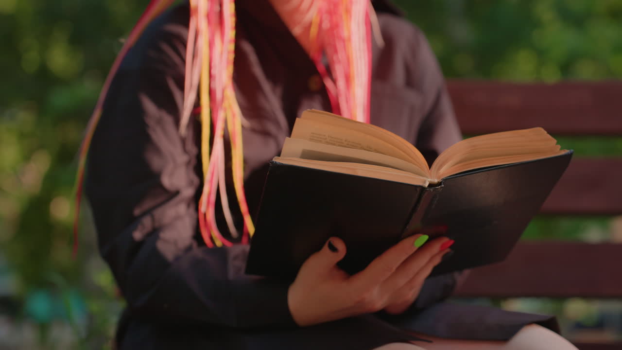 Scena di lettura al tramonto, persona che studia al parco durante il tramonto, lettore che si gode un momento di pace mentre il sole tramonta nel parco, persona assorta nella lettura seduta su una panchina al tramonto