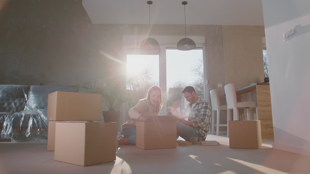 una pareja joven desempaquetando una nueva caja de cartón.