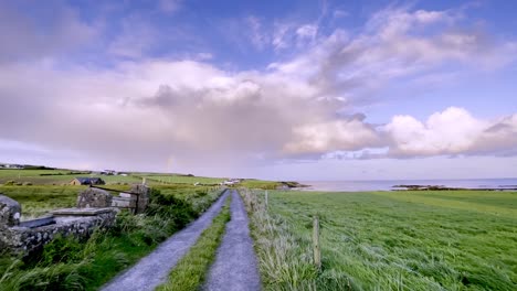 farmland in west cork, near kinsale, ireland with dramatic cloud and rainbow in the sky