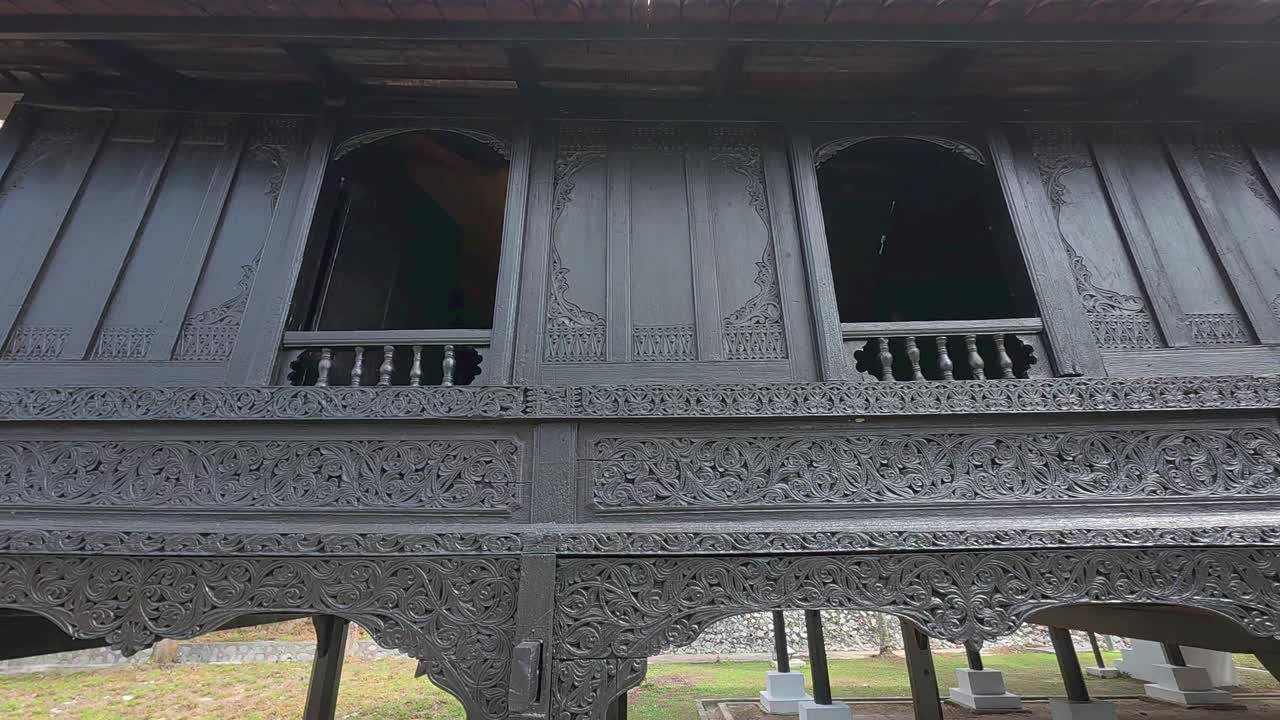 Floral wood carvings on a traditional Malay home. Skilled artistry and consistent style showcase authentic Malay architecture. Rich cultural heritage preserved in detailed woodwork.