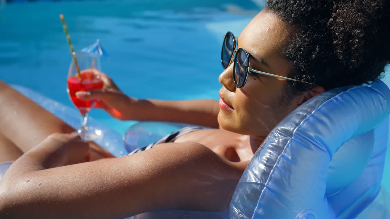 Close-up of young mixed-race woman relaxing on floating pool lounger in swimming pool 4k