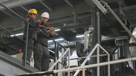 factory workers in helmets discussing work