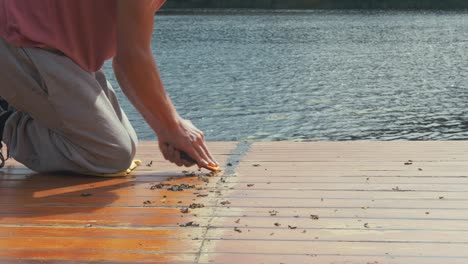 carpenter scraping sealant off wooden cabin roof