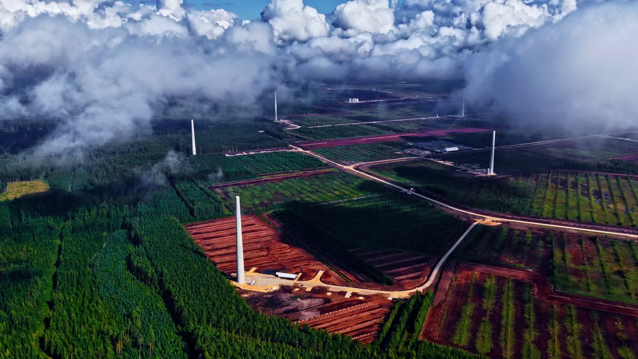Aerial view of an industry amidst the woods and fields under a cloudy sky