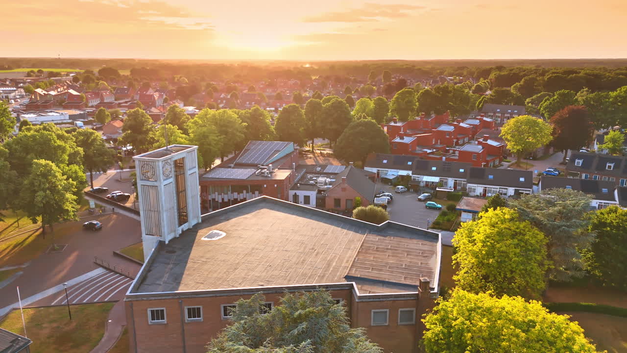Sunset over community homes. A peaceful residential area is illuminated by the warm colors of the setting sun, surrounded by lush green trees