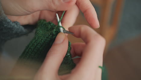 de handen van een onherkenbare vrouw die breit met groene wol 4