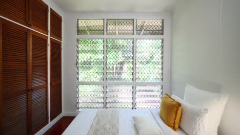 dolly between doorframe to modern home interior wooden flooring elevated property small bedroom and jalousie windows