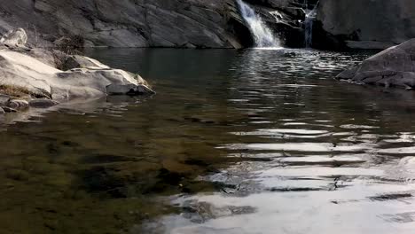 Tagsüber-Naher-Drohnenflug-über-Wasser-In-Der-Nähe-Eines-Wasserfalls