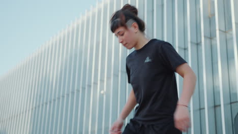 girl practicing juggling with soccer ball on urban street