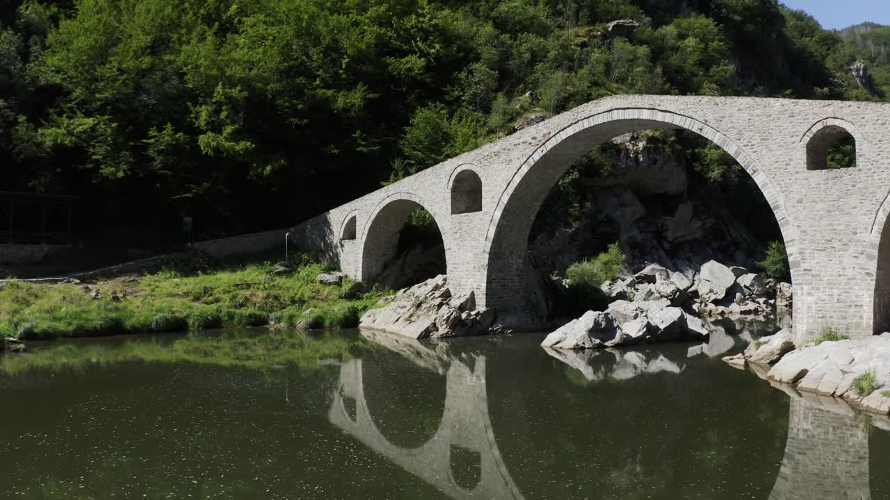Drone shot moving towards the main arch of the Devil's Bridge, located in Ardino, at the foot of the Rhodope Mountain in Bulgaria