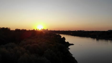Aerial-footage-of-sunset-overlooking-the-city-and-river,-warsaw
