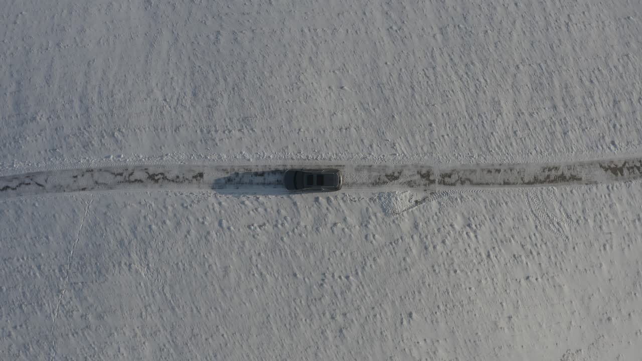 A black SUV passing through a snowy hillside