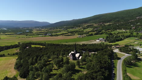 aerial shot of a wooden church with a graveyard, set among green fields and rural landscapes.