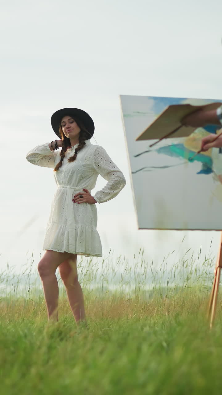 체크색 셔츠와 청바지를 입은 스케치 아티스트가 색 드레스와 모자를 입고 울창한 풀 속에서 포즈를 취하는 여성의 이미지를 포착합니다. 평온한 야외 환경은 창의적인 과정을 강조합니다.