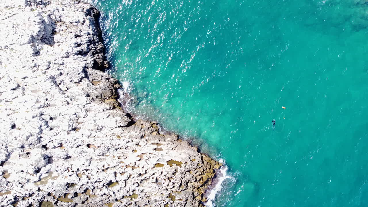 Ripresa aerea verticale dall'alto, persone che nuotano in acque costiere blu