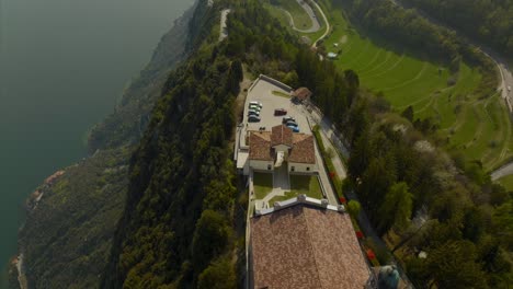 Cinematic-aerial-dolly-of-scenic-hilltop-village-comune-and-Sanctuary-of-Montecastello-overlooking-Lake-Garda-and-forest-trails