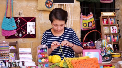 local seller threading yellow yarn through needle outside in nicosia. slow motion