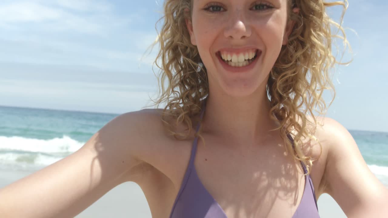 Vista frontale di donna caucasica che manda un bacio volante sulla spiaggia 4k
