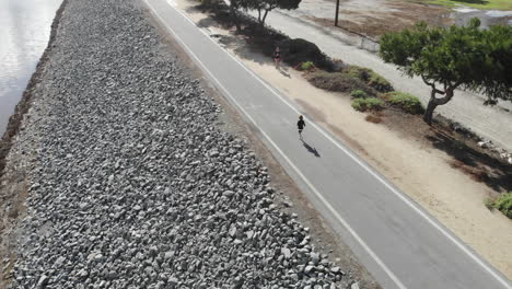 a 4k rotating aerial drone of a young boy as he runs along the riverbed for his daily workout.