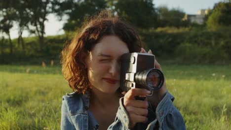 mujer filmando en un campo con una cámara vintage