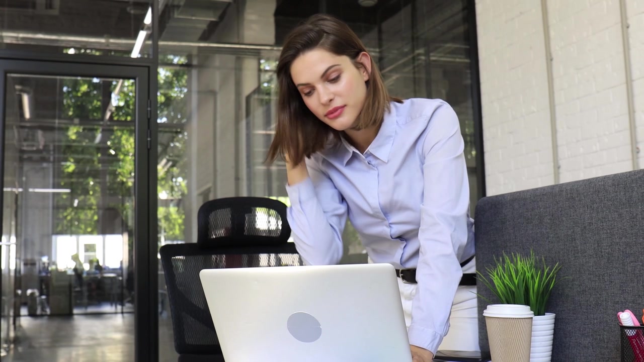 Joven empresaria de pie trabajando en su portátil en una oficina moderna
