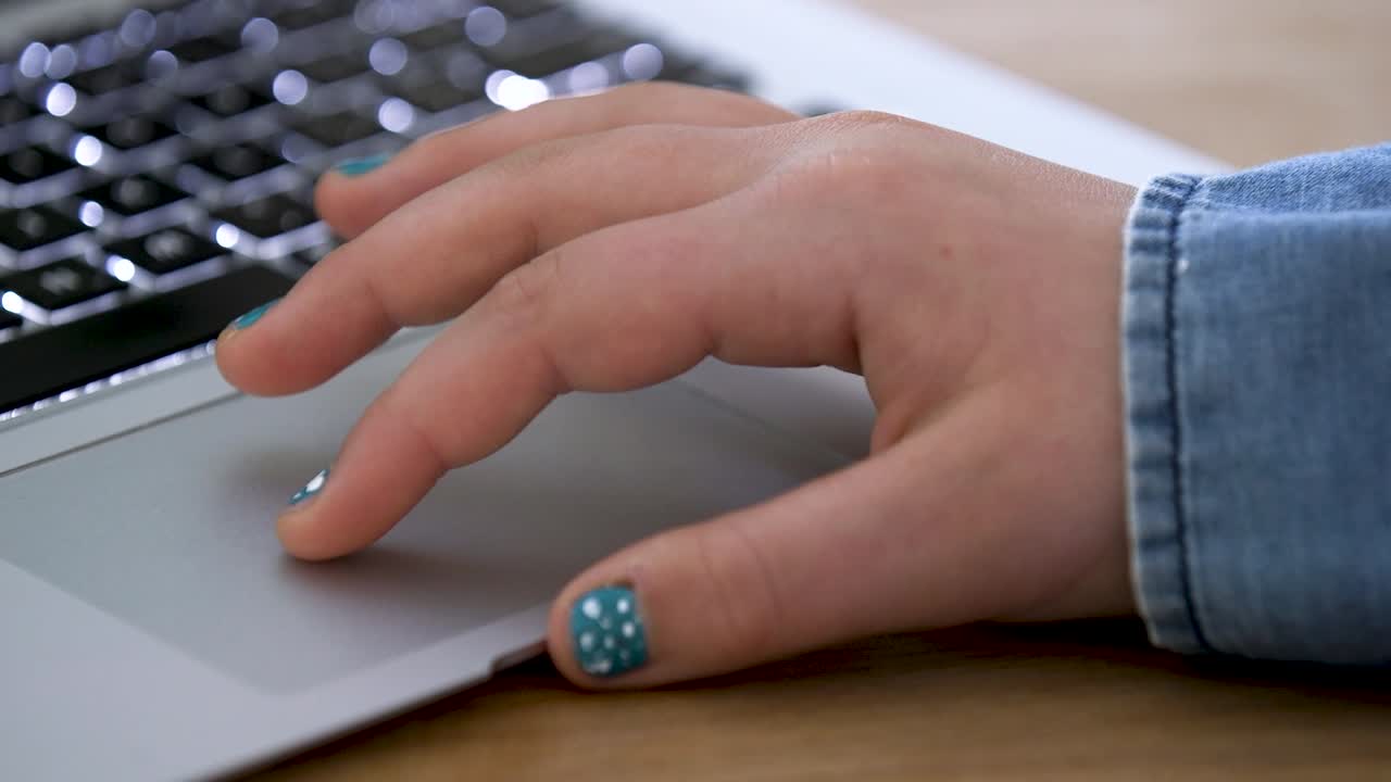 A closeup of a child's hand as they use a laptop