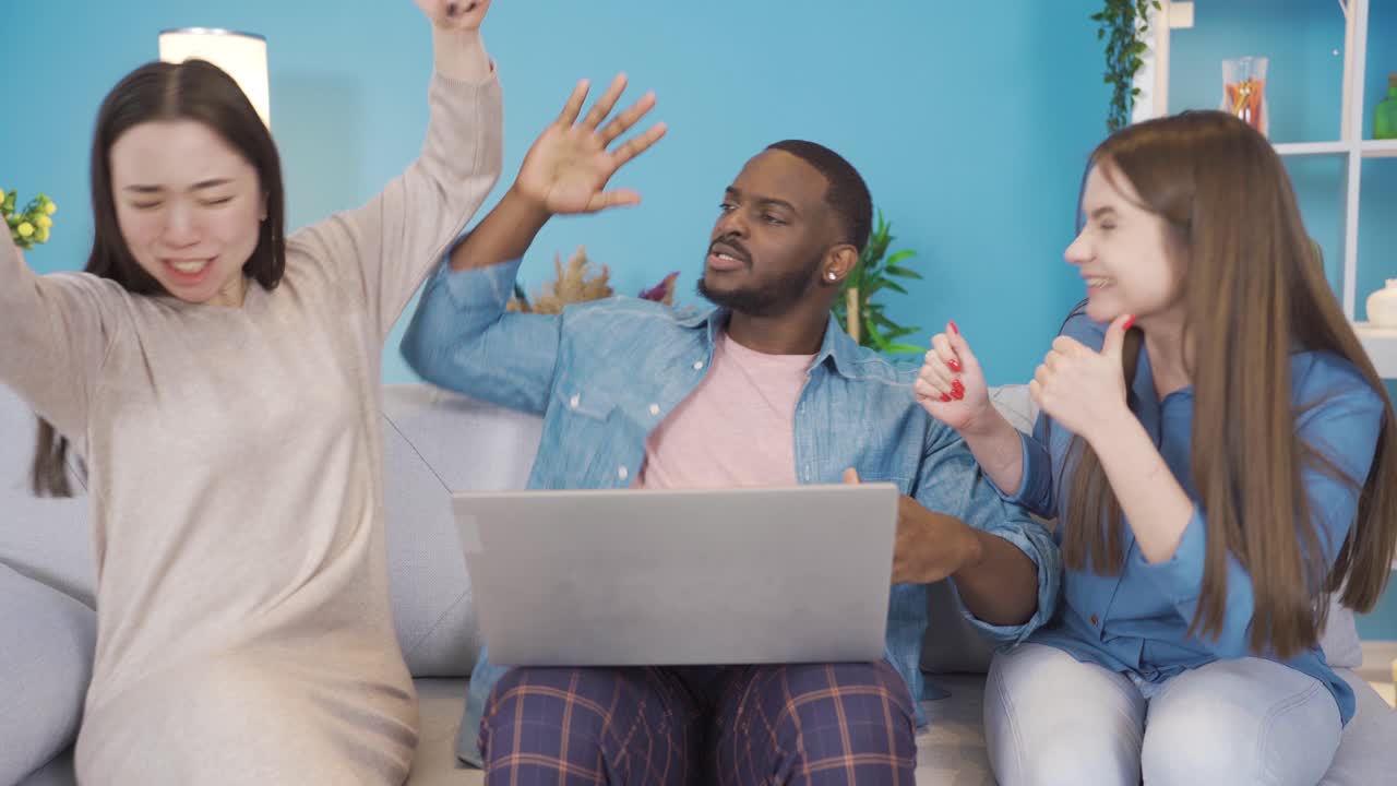 jóvenes de diferentes razas mirando la computadora portátil y regocijándose.