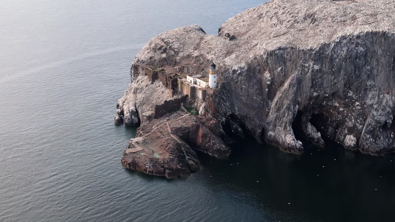 Aerial drone footage of Bass Rock, an island off the coast of North Berwick, Scotland, in the warm summer sunshine. North Sea, rugged cliffs, seabird colonies.