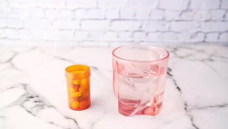 person reaching for pills in orange bottle