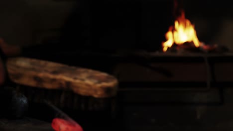 hand of blacksmith using wire brush on hot iron