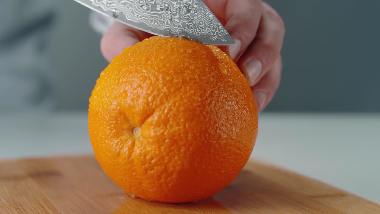 manteniendo la naranja firme mientras el cuchillo la corta por la mitad