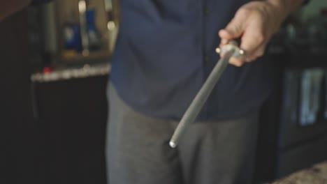 man sharpening knife with honing rod - close up