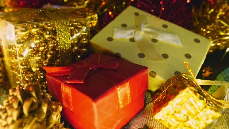 close up, stack of gift boxes under christmas tree with lights flashing in background, hand held