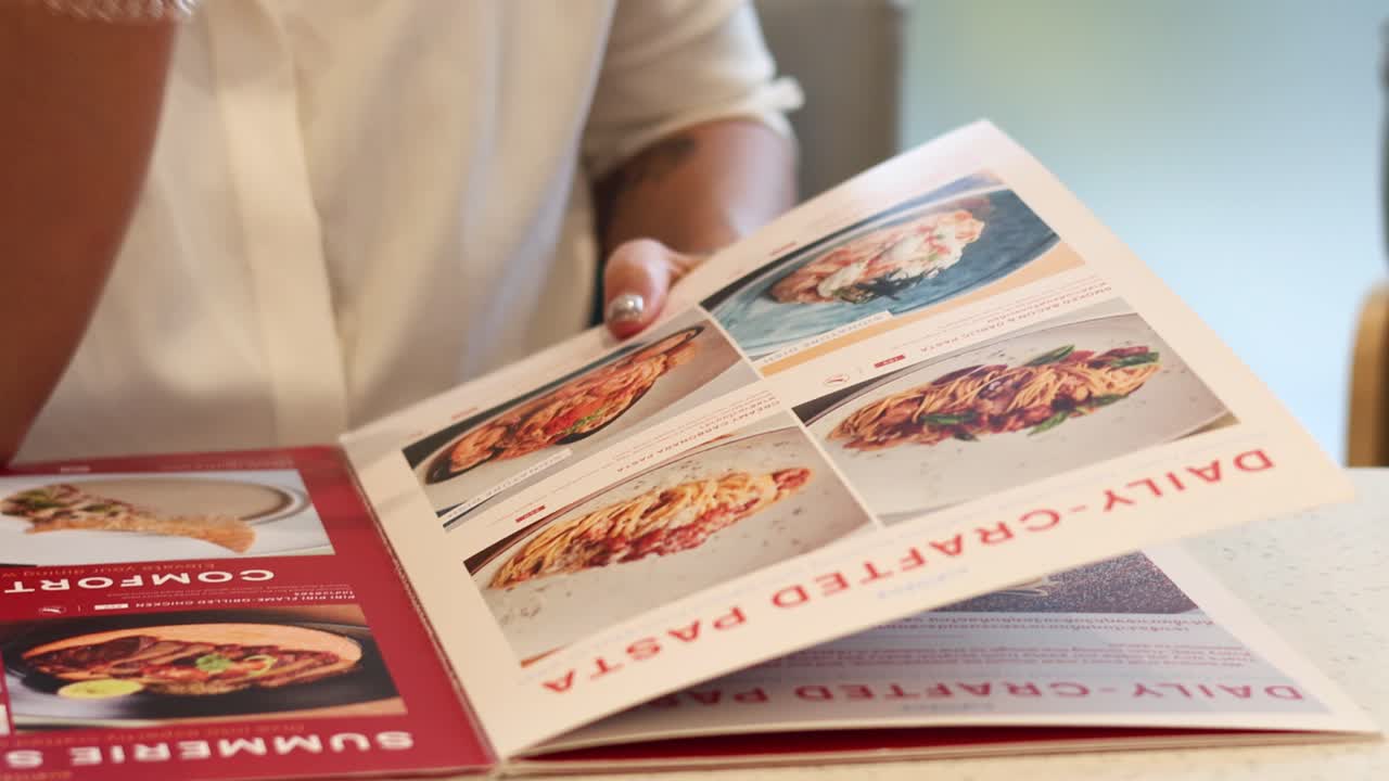 Person flipping through a food menu, making a choice