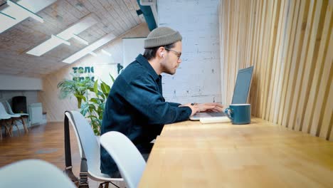 un joven está trabajando en una computadora portátil en un espacio de coworking.