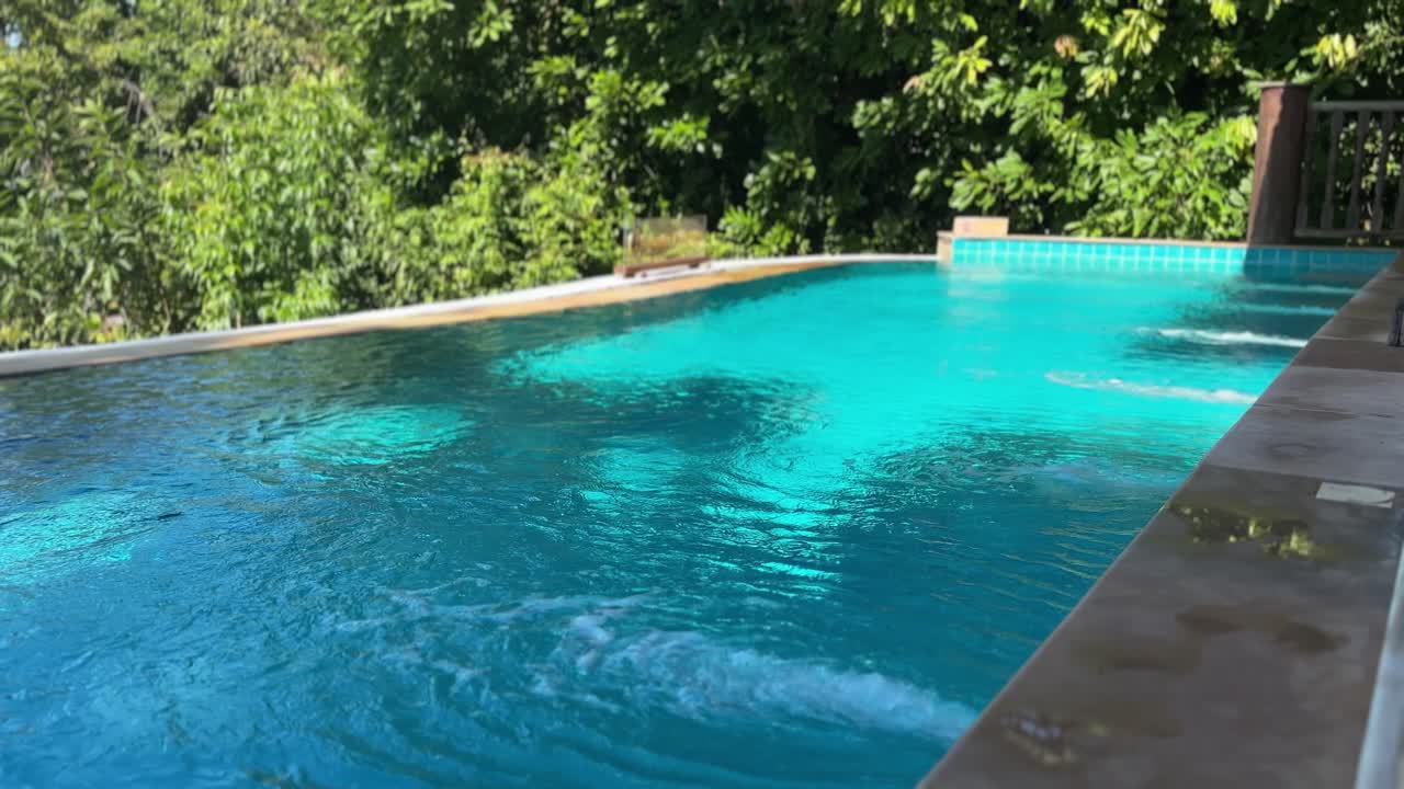 Privat swimmingpool ved luksusvilla på øen Koh Yao Yai i Thailand med klart, blåt vand, stenkant og frodig, tropisk skov, der skaber en rolig resortstemning