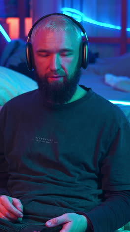 man listening to music on headphones in a neon lit room