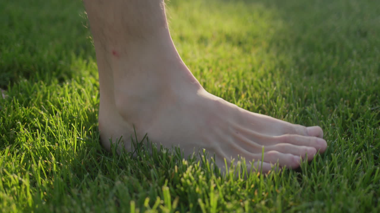 A man walks on green grass, leaves a trail. Blades of grass are restored