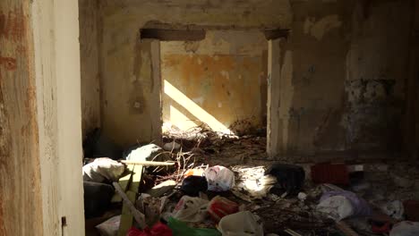 Tiro-A-Cámara-Lenta-En-Una-Casa-Abandonada-En-Un-Pueblo-Solitario-Con-Una-Habitación-Llena-De-Ropa-Vieja-Y-Basura