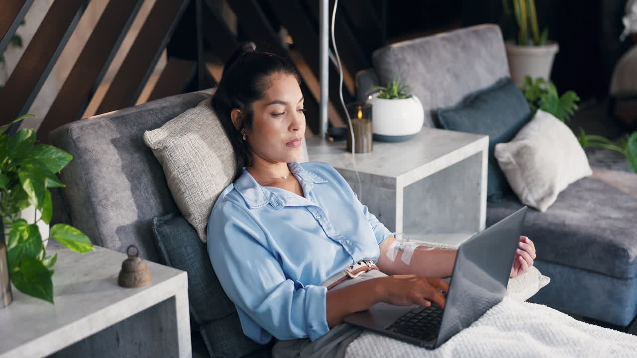 Woman with IV Drip Working on Laptop from Couch