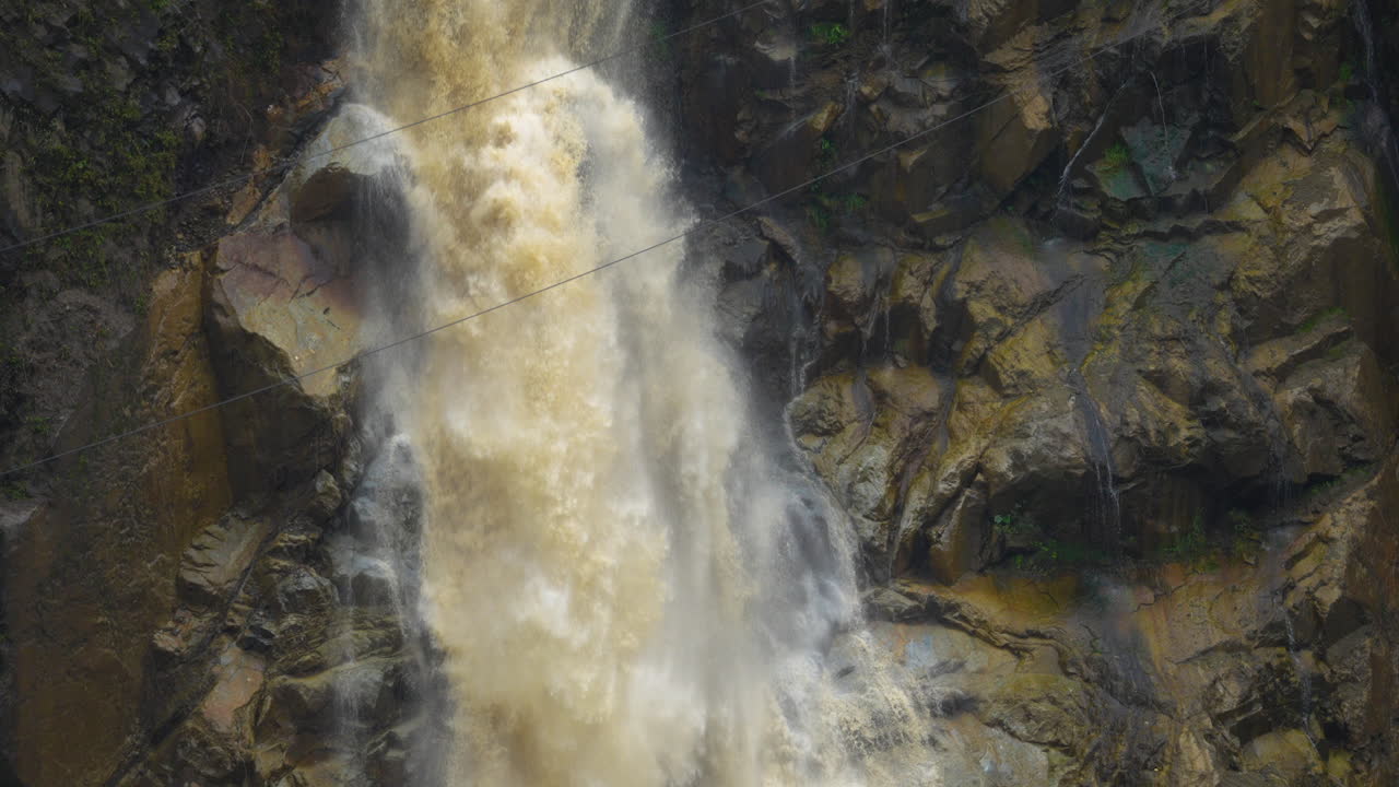 agua sucia cayendo por la cascada en cámara lenta a lo largo de la pared rocosa del acantilado húmedo - baños, ecuador