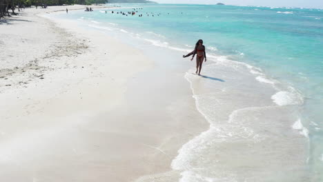 aerial - caribbean holiday vibes, female beachgoer strolls on white sand beach near puerto plata, dominican republic