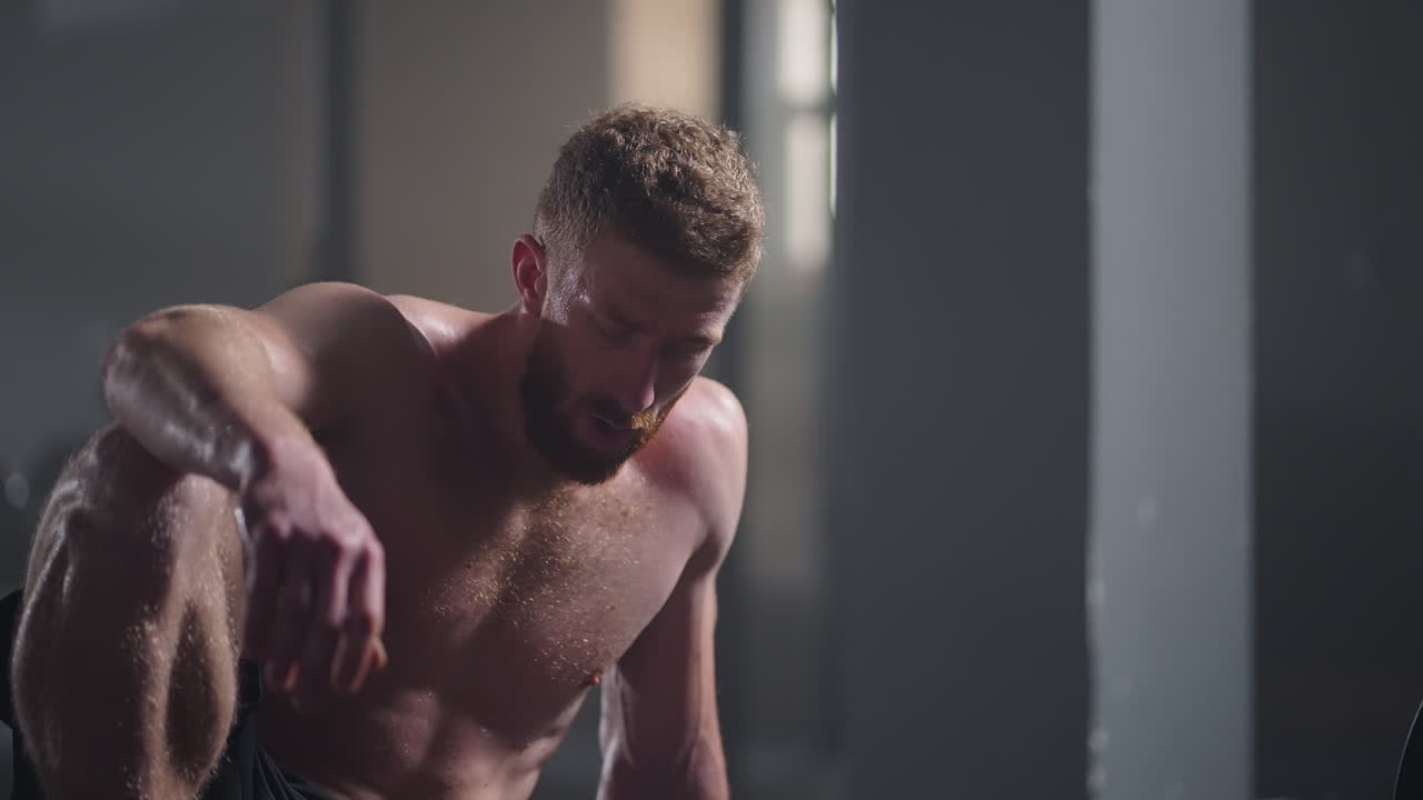 체육관에서 집중적인 운동을 한 후 휴식을 취하는 지친 젊은 남성. 체육관에서 근력 훈련 운동을 한 후 피곤한 건강한 남성. 강렬한 운동을 한 후 서서 휴식을 취하는 피곤한 남성 피트 모델.