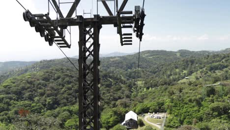 Handheld-footage-from-an-aerial-tram-traveling-uphill-from-the-sky-tram-station,-with-background-panoramic-views-of-a-tropical-rainforest