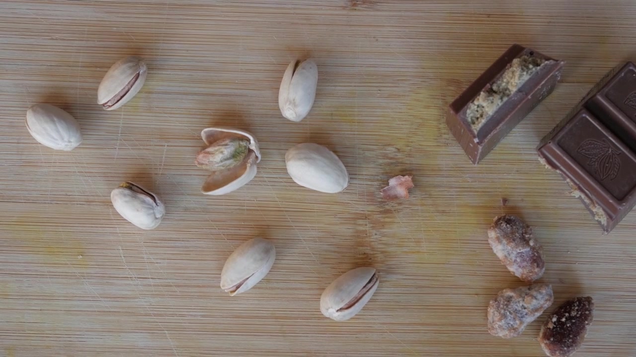 Pistachios scattered on a wooden board, hinting at Dubai chocolate