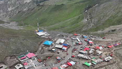 aerial flying over mountain top shops and huts to reveal winding road at babusar pass