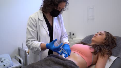 cosmetólogo haciendo una inyección en el vientre de la mujer