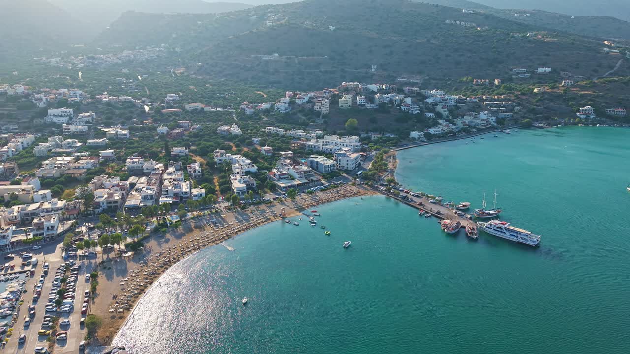 High angle view of the sandy beach, turquoise bay, and boats in Elounda, Crete